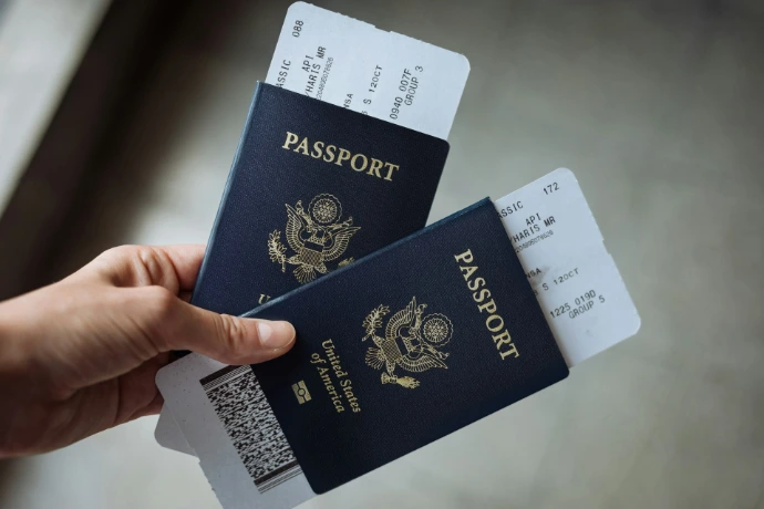 A hand holding two United States passports with airline boarding passes tucked inside